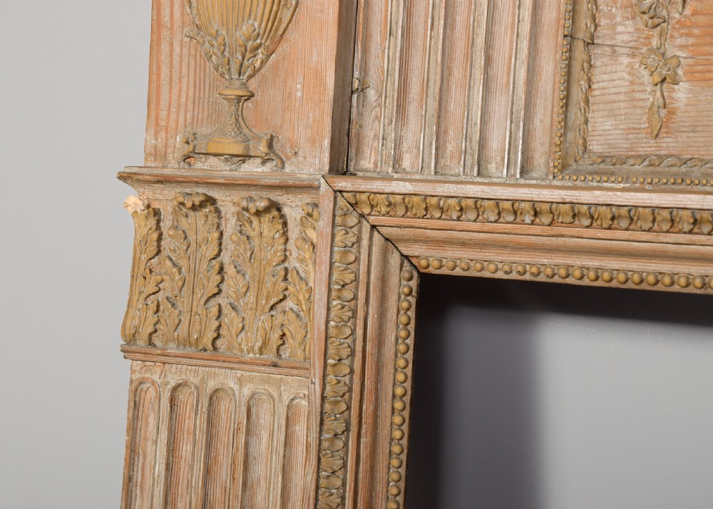 A George III carved pine and gesso fireplace surround featuring fluted jambs, classical urn motifs, and a detailed frieze. View IV