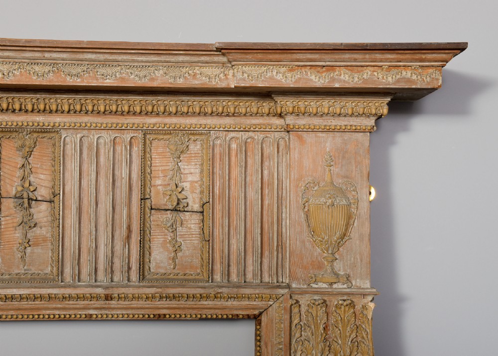 A George III carved pine and gesso fireplace surround featuring fluted jambs, classical urn motifs, and a detailed frieze. View VII
