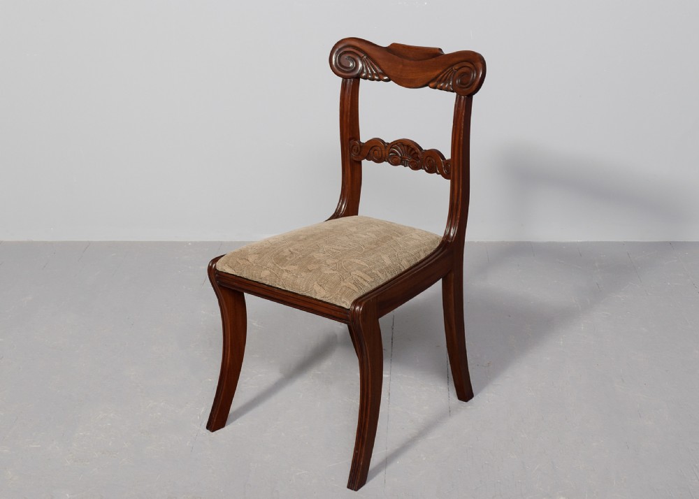 A set of ten Scottish carved mahogany dining chairs featuring cresting bar backs, carved splats, neutral fabric seats, and curved sabre front legs. View III