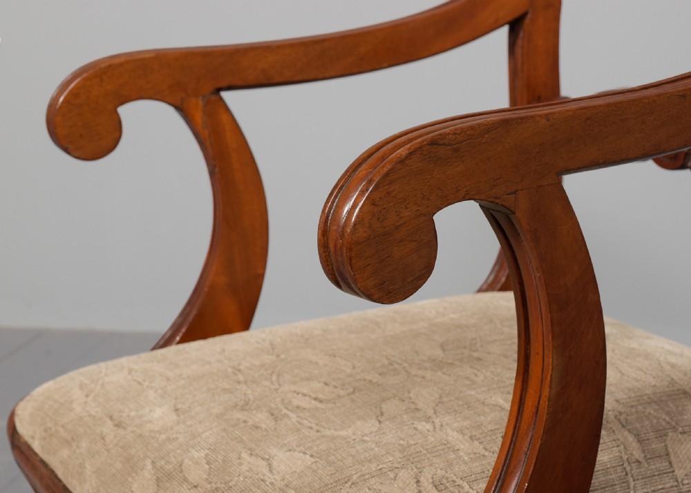 A set of ten Scottish carved mahogany dining chairs featuring cresting bar backs, carved splats, neutral fabric seats, and curved sabre front legs. View VIII
