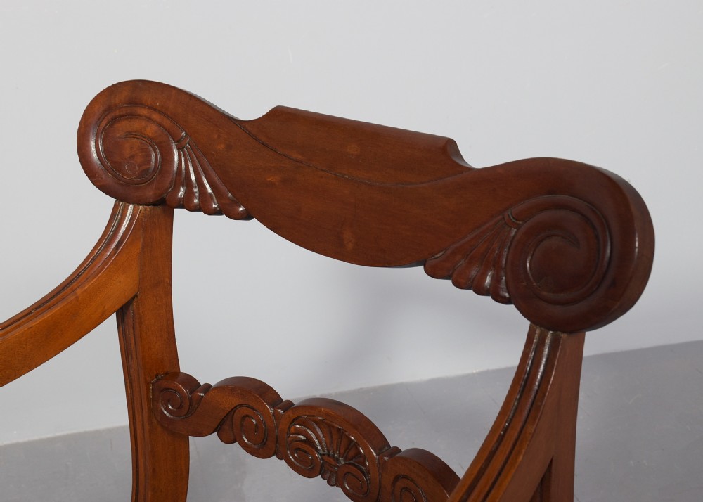 A set of ten Scottish carved mahogany dining chairs featuring cresting bar backs, carved splats, neutral fabric seats, and curved sabre front legs. View XII