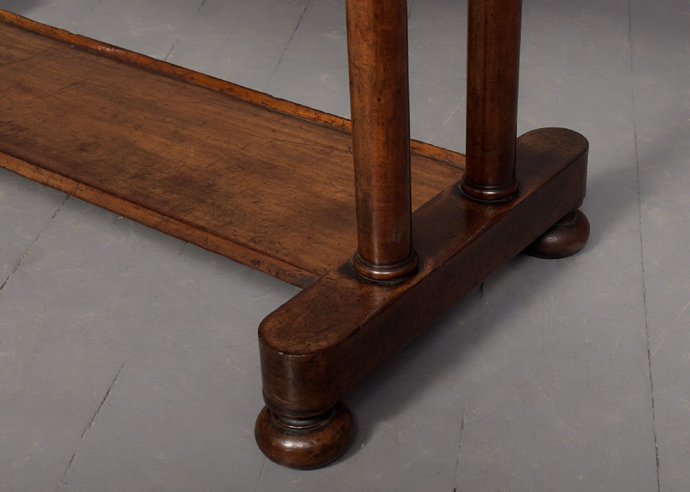 A William IV mahogany side table featuring a low gallery upstand, a long frieze drawer with round wooden knobs, twin turned end supports, a low stretcher, and bun feet. View VI