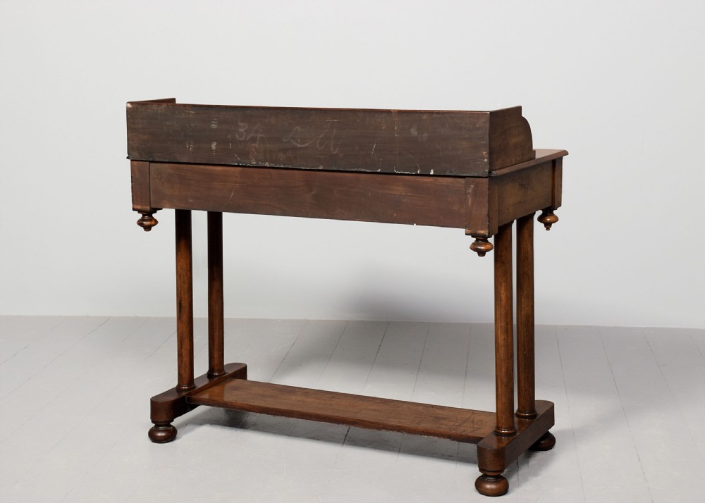 A William IV mahogany side table featuring a low gallery upstand, a long frieze drawer with round wooden knobs, twin turned end supports, a low stretcher, and bun feet. View IX