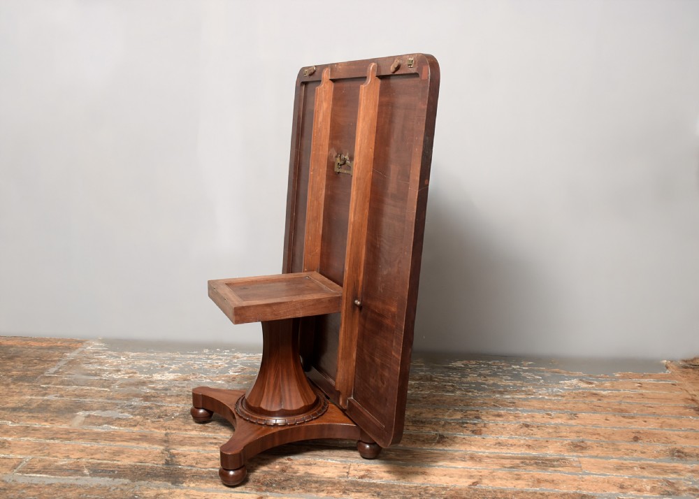 A William IV twin-pedestal dining table crafted from dark figured mahogany with rounded corners and plinth bases on bun feet. View VII