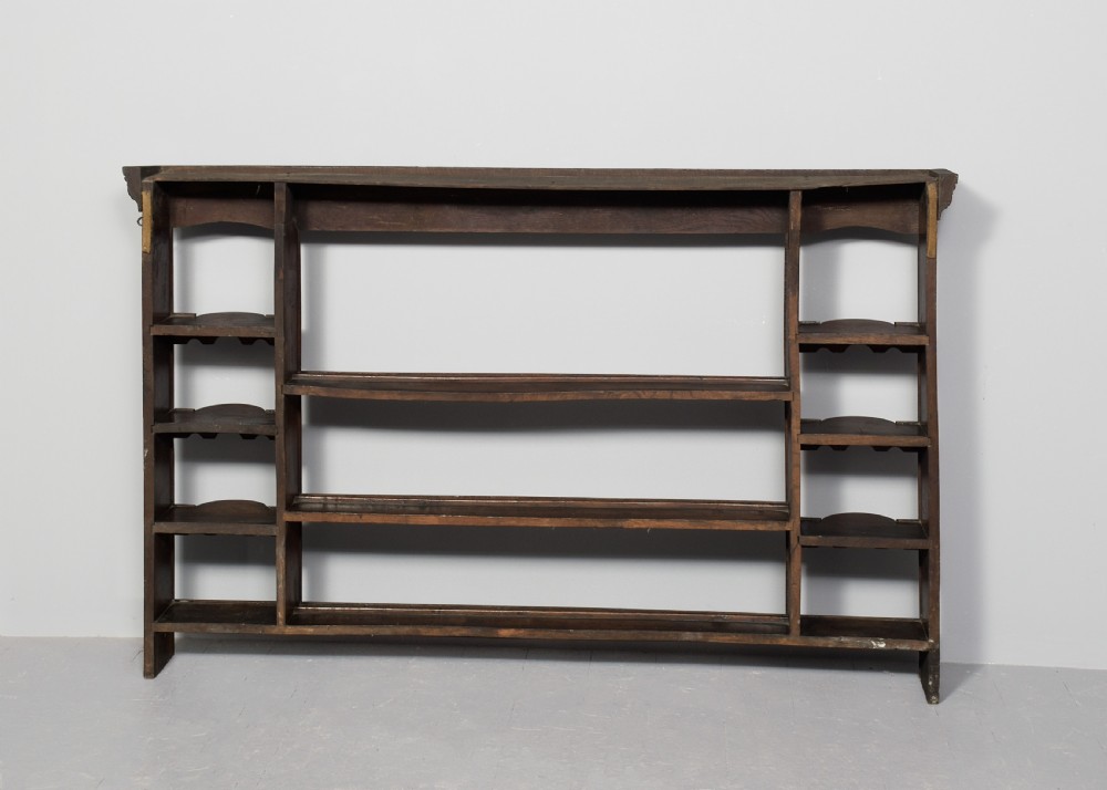 An 18th-century George III dark oak wall rack featuring a moulded cornice, three open central shelves, and vertical side compartments. View VII