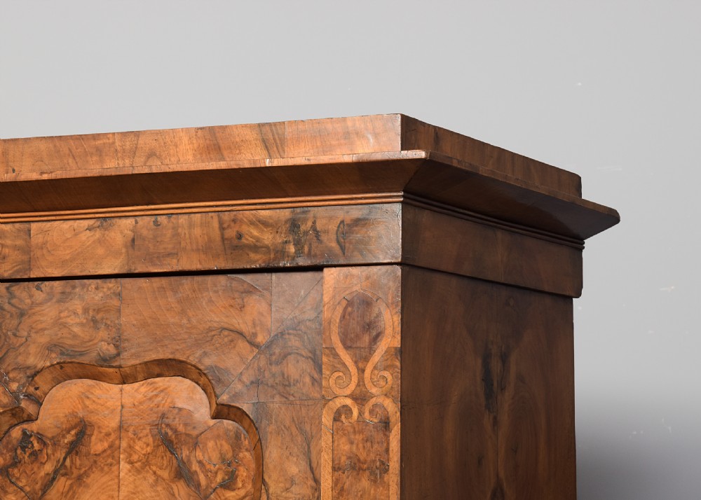 A tall two-door freestanding armoire in figured walnut veneer with shaped door panels, a straight moulded cornice, and plinth base with bracket feet. View II