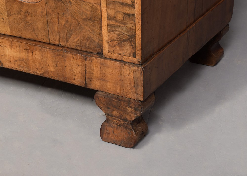 A tall two-door freestanding armoire in figured walnut veneer with shaped door panels, a straight moulded cornice, and plinth base with bracket feet. View III