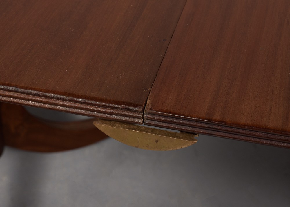 A Georgian style twin pedestal dining table crafted from dark brown Spanish mahogany featuring splayed legs with brass castors and a removable central leaf. View IV