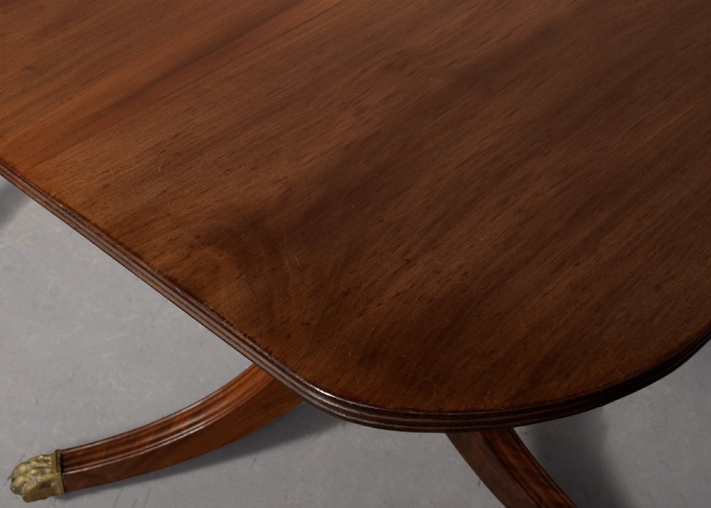 A Georgian style twin pedestal dining table crafted from dark brown Spanish mahogany featuring splayed legs with brass castors and a removable central leaf. View V