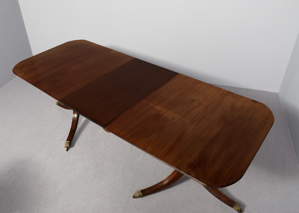 A Georgian style twin pedestal dining table crafted from dark brown Spanish mahogany featuring splayed legs with brass castors and a removable central leaf. View VII