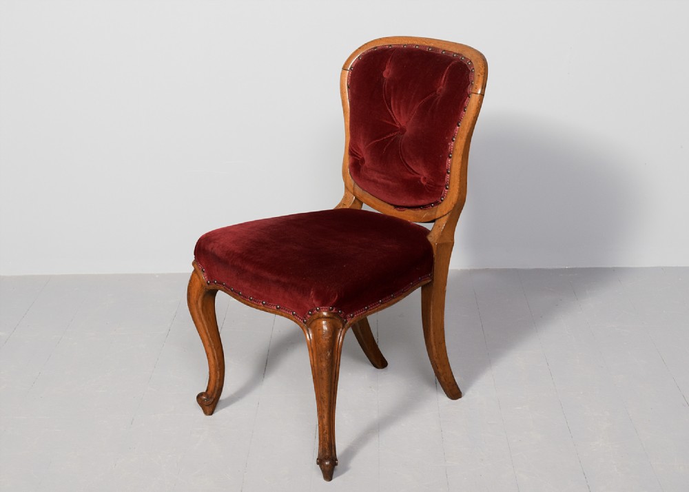 A set of twelve French carved oak dining chairs with balloon backs, cabriole legs, and red velvet or patterned fabric upholstery. View III