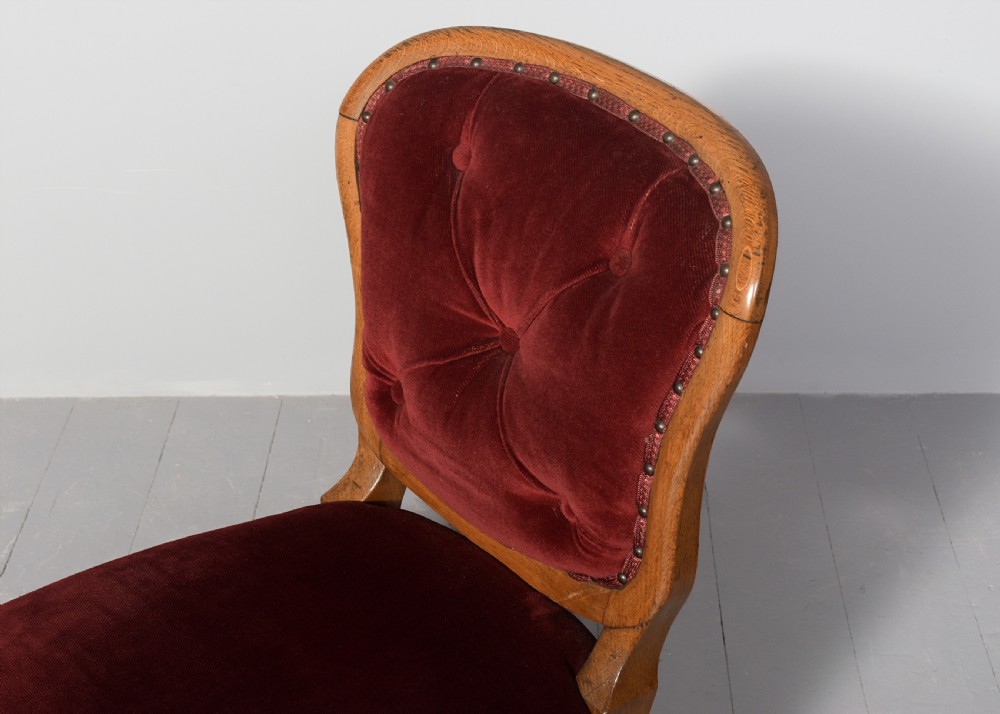 A set of twelve French carved oak dining chairs with balloon backs, cabriole legs, and red velvet or patterned fabric upholstery. View IV