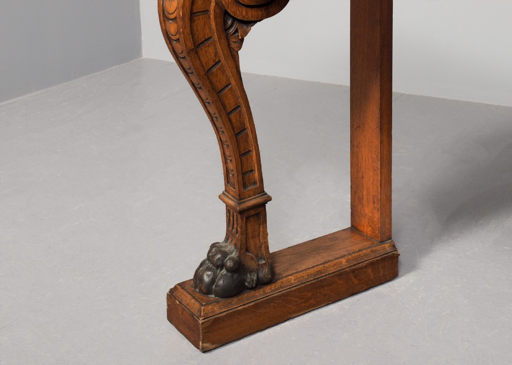 An antique oak console table featuring a polished pink granite top and heavy carved scroll legs ending in carved paw feet. View V