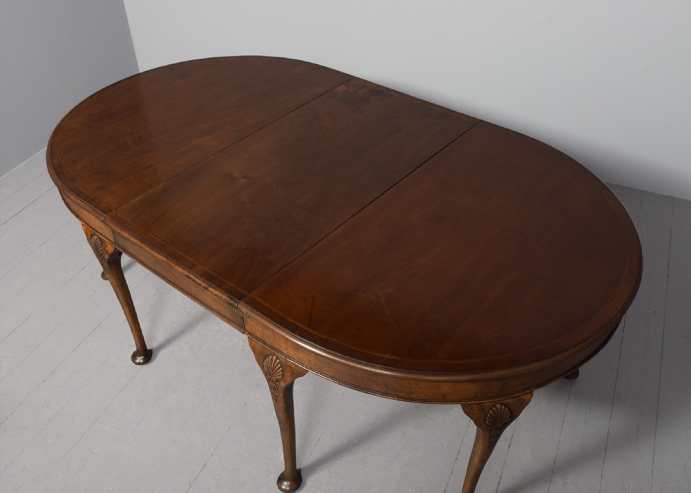 A George II style walnut extending dining table with carved cabriole legs, shell-detailed knees, and pad feet. View V