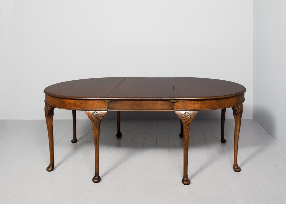 A George II style walnut extending dining table with carved cabriole legs, shell-detailed knees, and pad feet. View VI