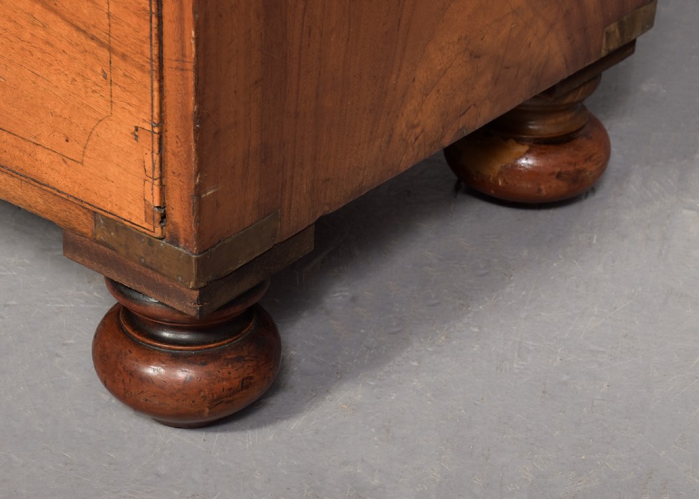 A two-part 19th-century camphor wood campaign chest featuring flush brass corners, recessed brass handles, and turned bun feet. View VII