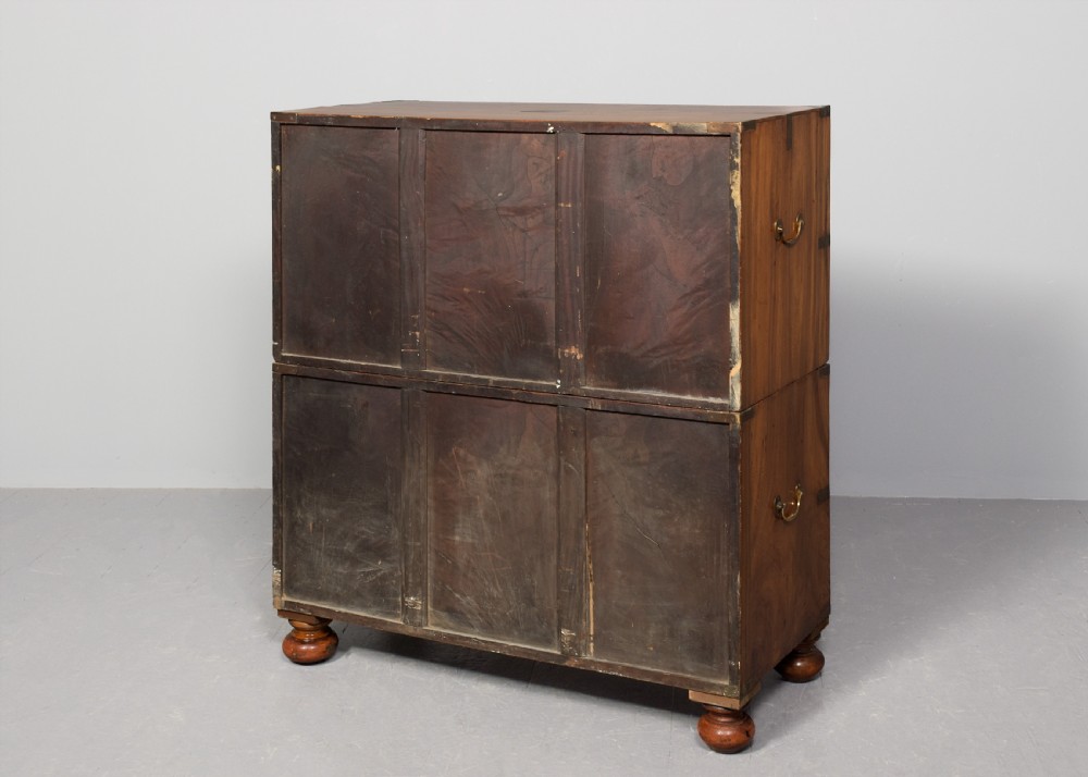 A two-part 19th-century camphor wood campaign chest featuring flush brass corners, recessed brass handles, and turned bun feet. View X