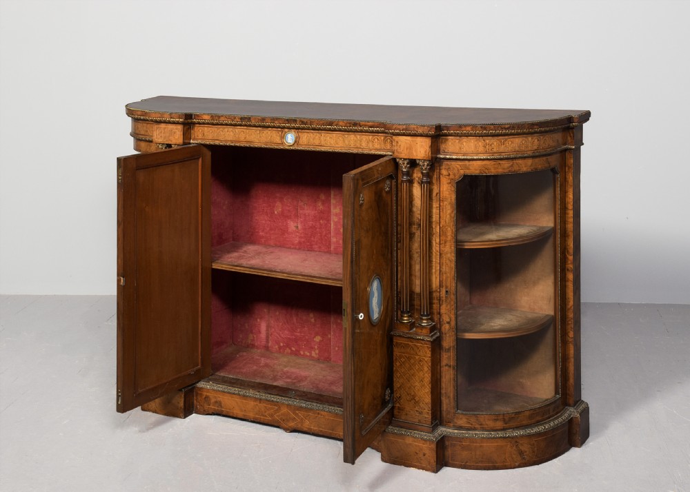 A Victorian burr walnut credenza featuring curved glazed end display sections, twin central cupboard doors decorated with blue Jasperware plaques, and gilt metal mounts. View II