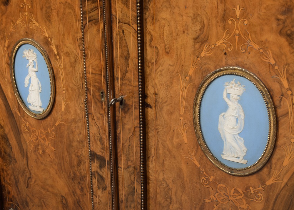 A Victorian burr walnut credenza featuring curved glazed end display sections, twin central cupboard doors decorated with blue Jasperware plaques, and gilt metal mounts. View VII