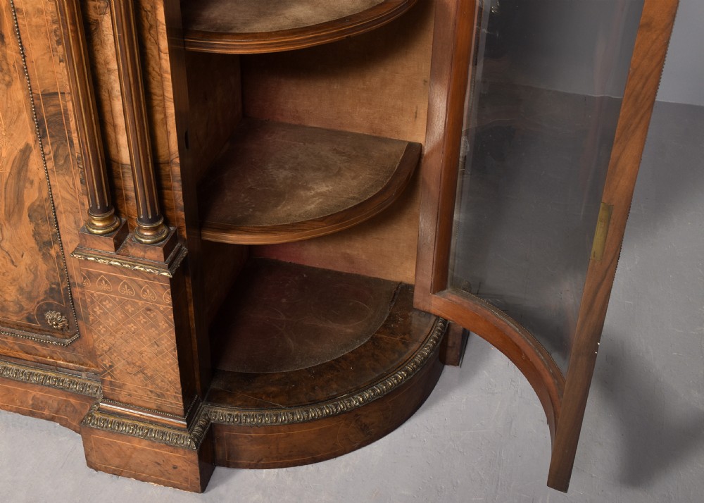 A Victorian burr walnut credenza featuring curved glazed end display sections, twin central cupboard doors decorated with blue Jasperware plaques, and gilt metal mounts. View X