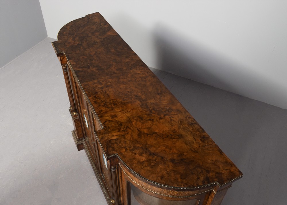 A Victorian burr walnut credenza featuring curved glazed end display sections, twin central cupboard doors decorated with blue Jasperware plaques, and gilt metal mounts. View XII