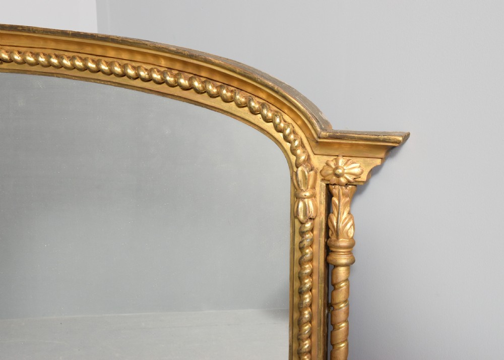 An arched antique giltwood overmantel mirror featuring beaded moulding and detailed side columns. View II