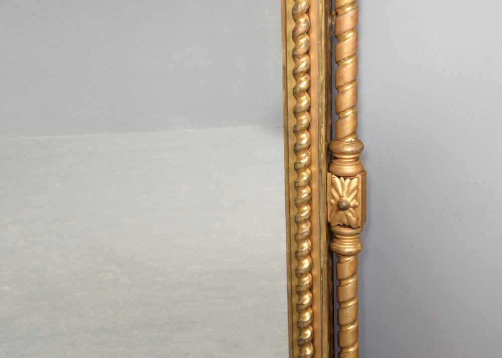 An arched antique giltwood overmantel mirror featuring beaded moulding and detailed side columns. View III