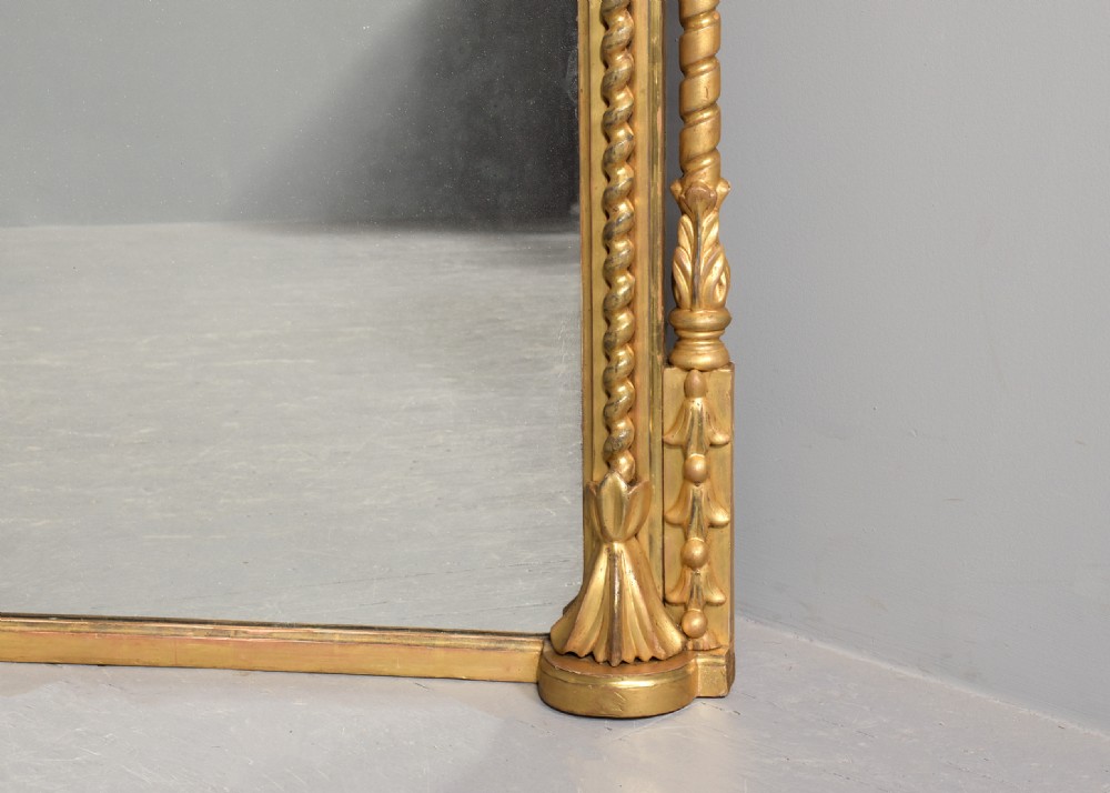 An arched antique giltwood overmantel mirror featuring beaded moulding and detailed side columns. View IV