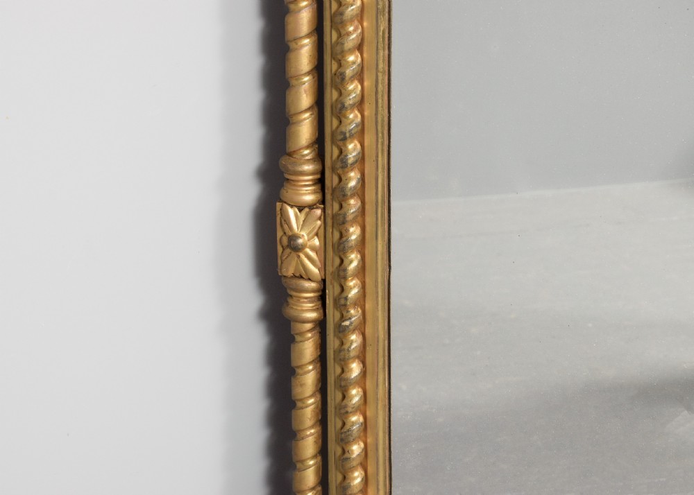 An arched antique giltwood overmantel mirror featuring beaded moulding and detailed side columns. View VI