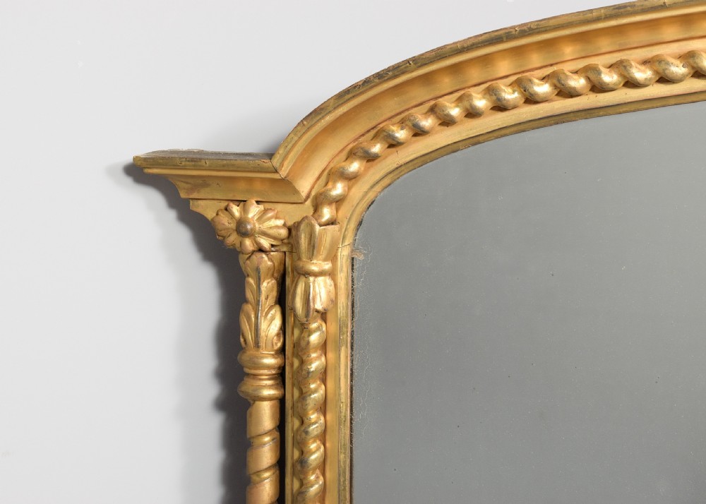 An arched antique giltwood overmantel mirror featuring beaded moulding and detailed side columns. View VII