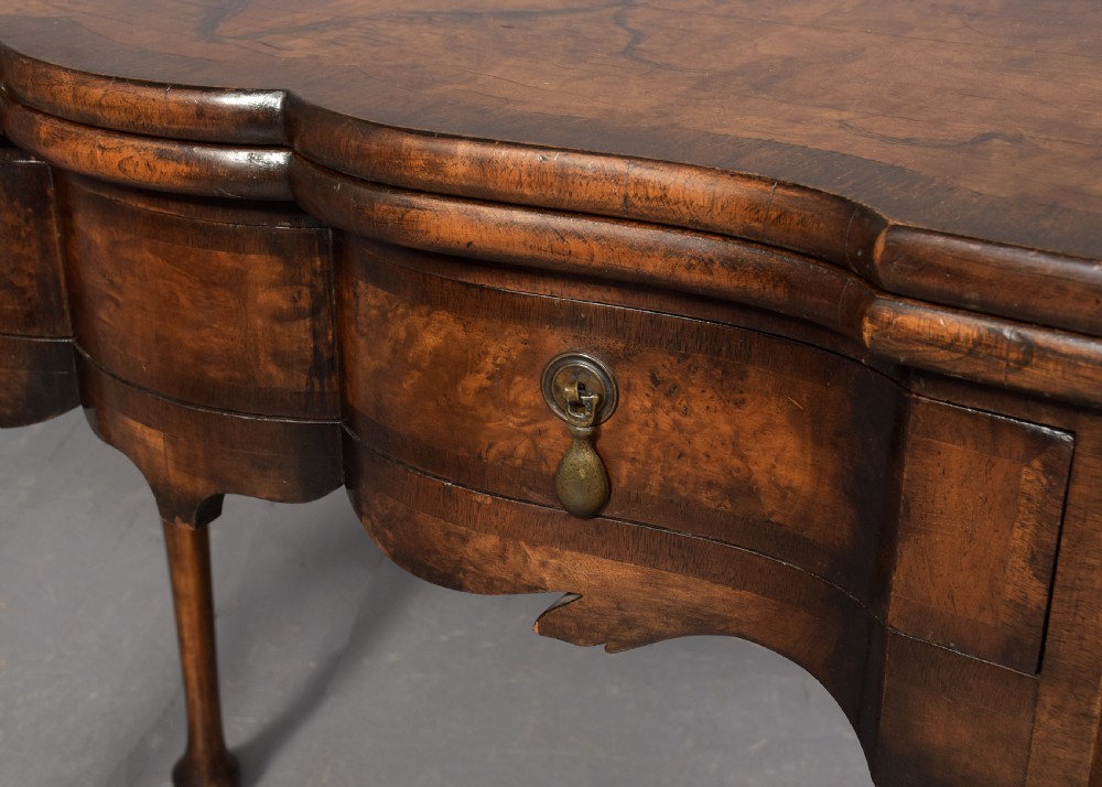 An early Georgian style fold-over walnut games table featuring a shaped top, frieze drawers with brass drop handles, and cabriole legs on pad feet. View III