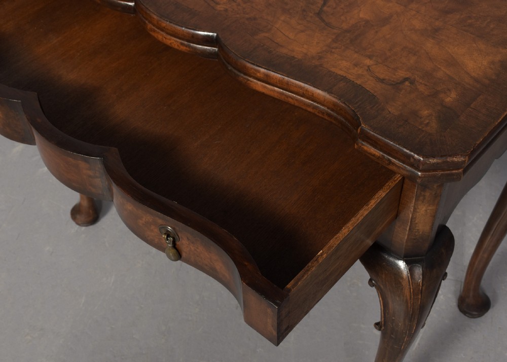 An early Georgian style fold-over walnut games table featuring a shaped top, frieze drawers with brass drop handles, and cabriole legs on pad feet. View V
