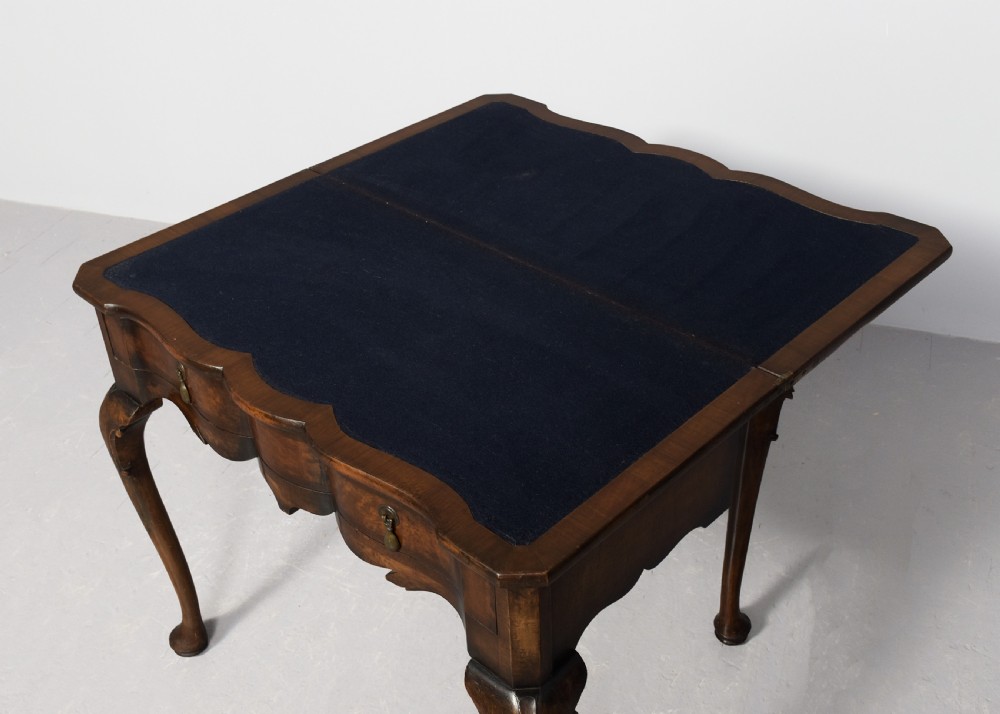 An early Georgian style fold-over walnut games table featuring a shaped top, frieze drawers with brass drop handles, and cabriole legs on pad feet. View VIII
