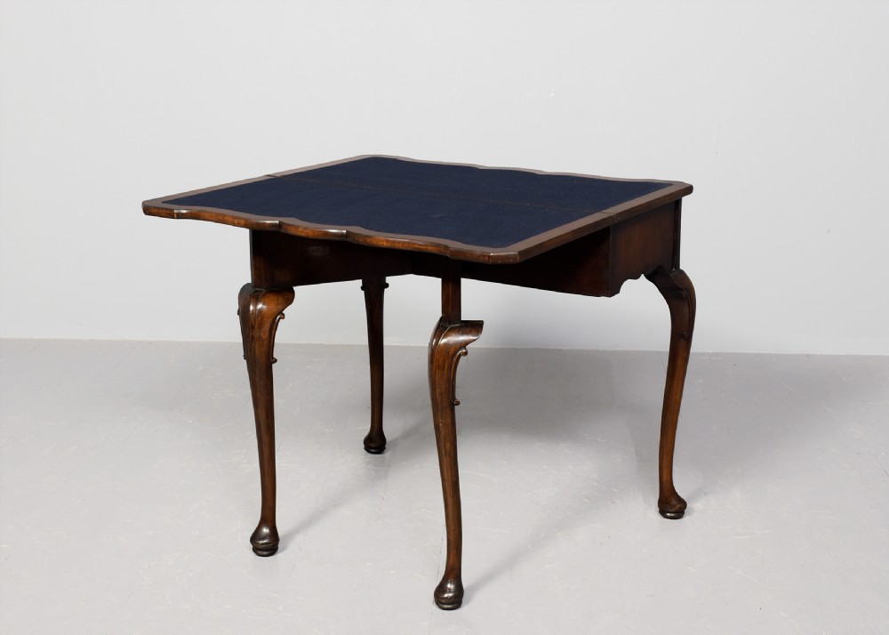 An early Georgian style fold-over walnut games table featuring a shaped top, frieze drawers with brass drop handles, and cabriole legs on pad feet. View IX