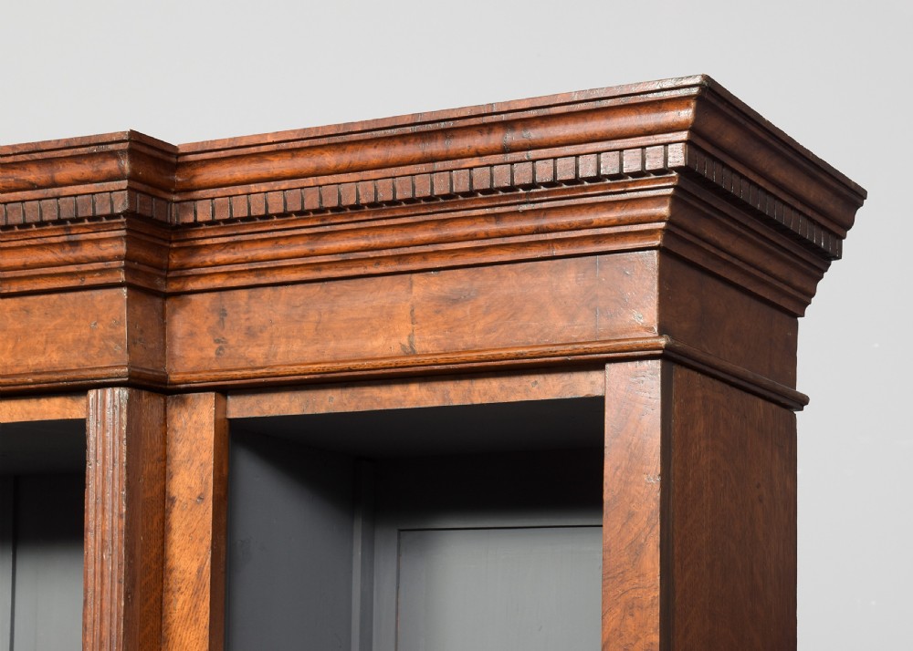 A tall Victorian breakfront open bookcase in pollard oak featuring three sections and grey painted backboards. View IV