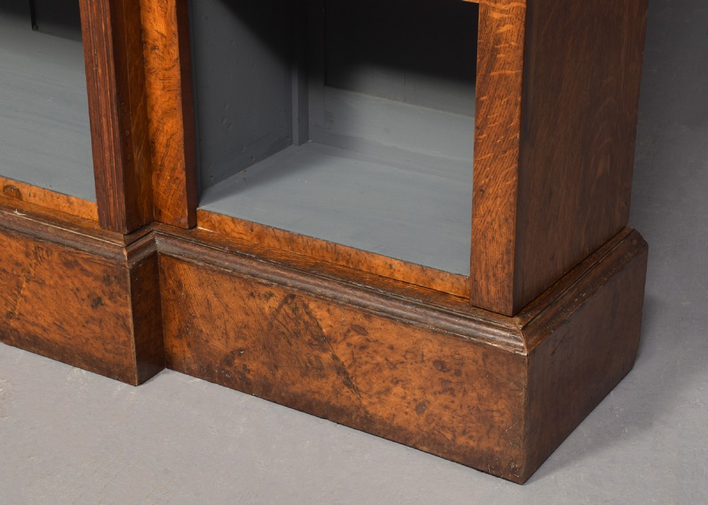 A tall Victorian breakfront open bookcase in pollard oak featuring three sections and grey painted backboards. View VI