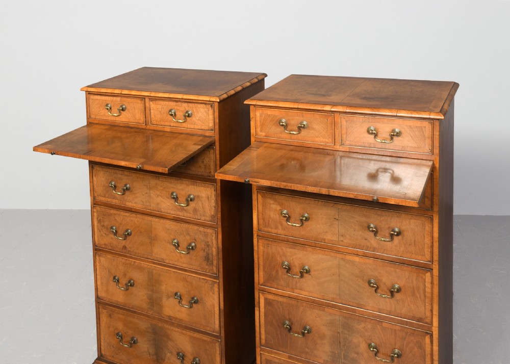 A pair of tall, narrow George III style walnut chests of drawers featuring figure-matched veneer fronts, brass swan-neck handles, and bracket feet. View III