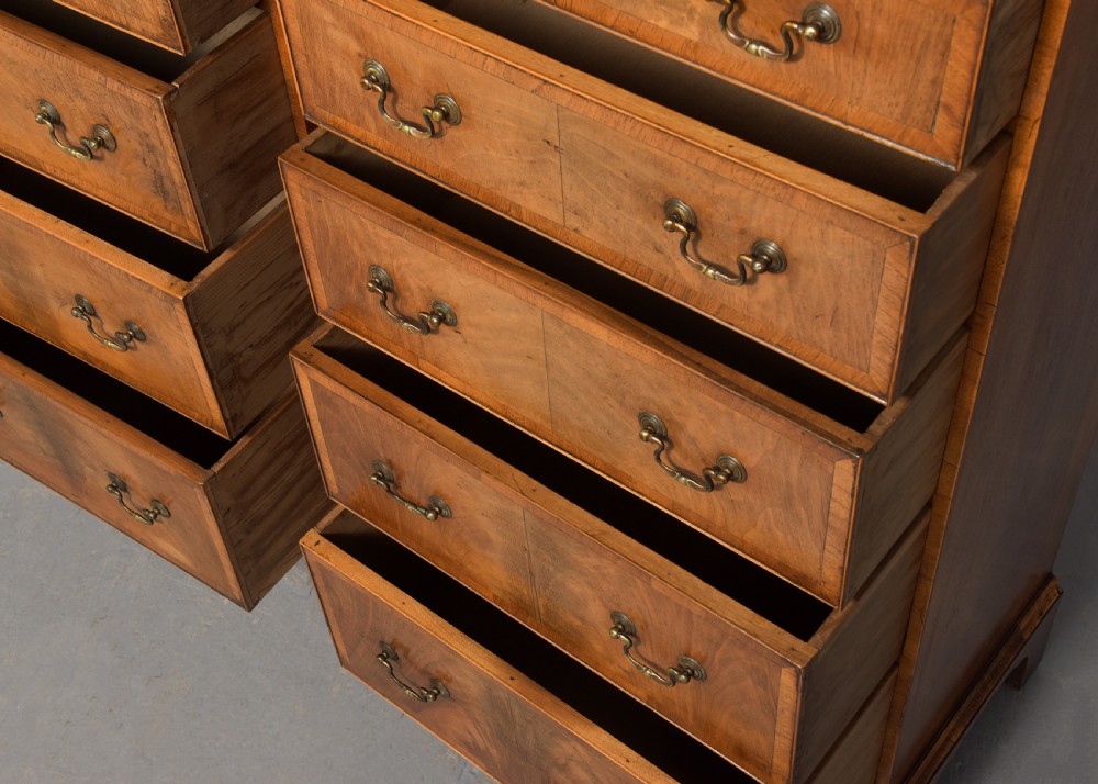 A pair of tall, narrow George III style walnut chests of drawers featuring figure-matched veneer fronts, brass swan-neck handles, and bracket feet. View VII