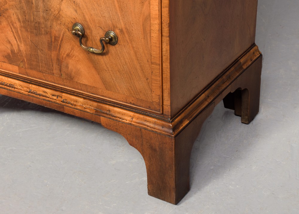 A pair of tall, narrow George III style walnut chests of drawers featuring figure-matched veneer fronts, brass swan-neck handles, and bracket feet. View VIII