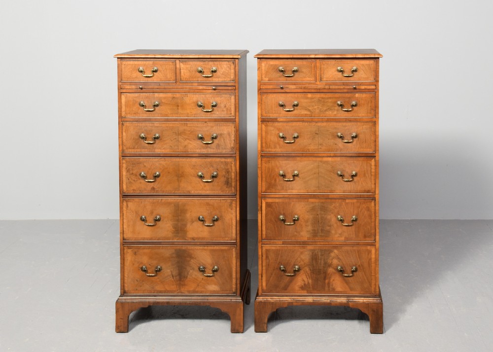 A pair of tall, narrow George III style walnut chests of drawers featuring figure-matched veneer fronts, brass swan-neck handles, and bracket feet. View IX
