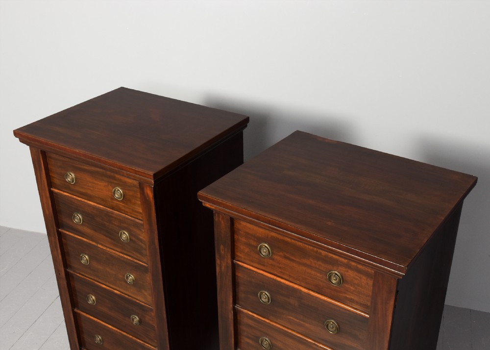 A pair of tall Victorian mahogany Wellington chests, each featuring six graduated drawers with brass handles and side locking stiles set on a plinth base. View VII