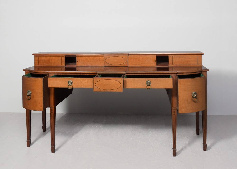 A George III mahogany stage-back sideboard featuring a raised upper tier, oval inlay detailing, brass lion-mask ring pulls, and tapered square legs. View II