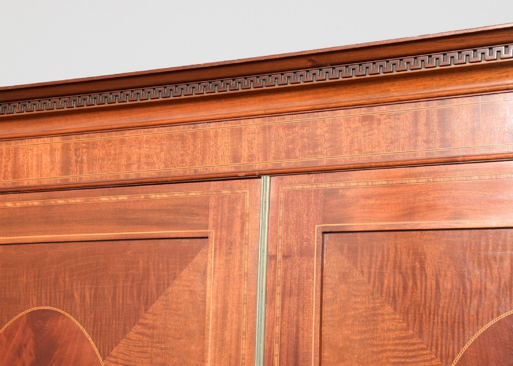 A two-door Georgian style mahogany wardrobe featuring flame mahogany oval veneer panels, fine boxwood stringing, and bracket feet. View V