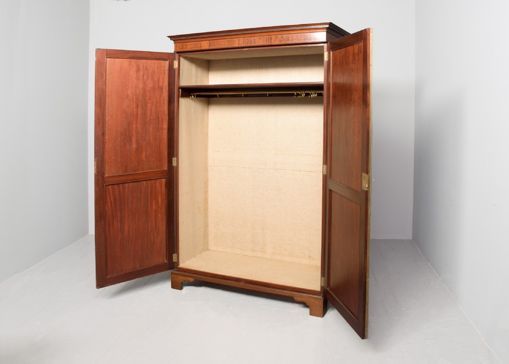 A two-door Georgian style mahogany wardrobe featuring flame mahogany oval veneer panels, fine boxwood stringing, and bracket feet. View VI