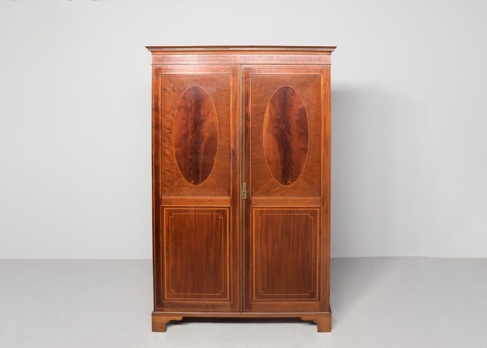 A two-door Georgian style mahogany wardrobe featuring flame mahogany oval veneer panels, fine boxwood stringing, and bracket feet. View VII