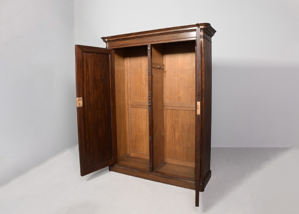 A William IV flame mahogany double wardrobe featuring fielded panel doors, a moulded cornice, and a plinth base. View V