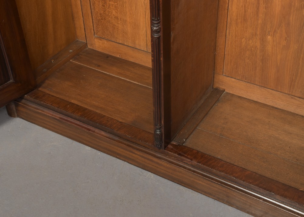 A William IV flame mahogany double wardrobe featuring fielded panel doors, a moulded cornice, and a plinth base. View VII