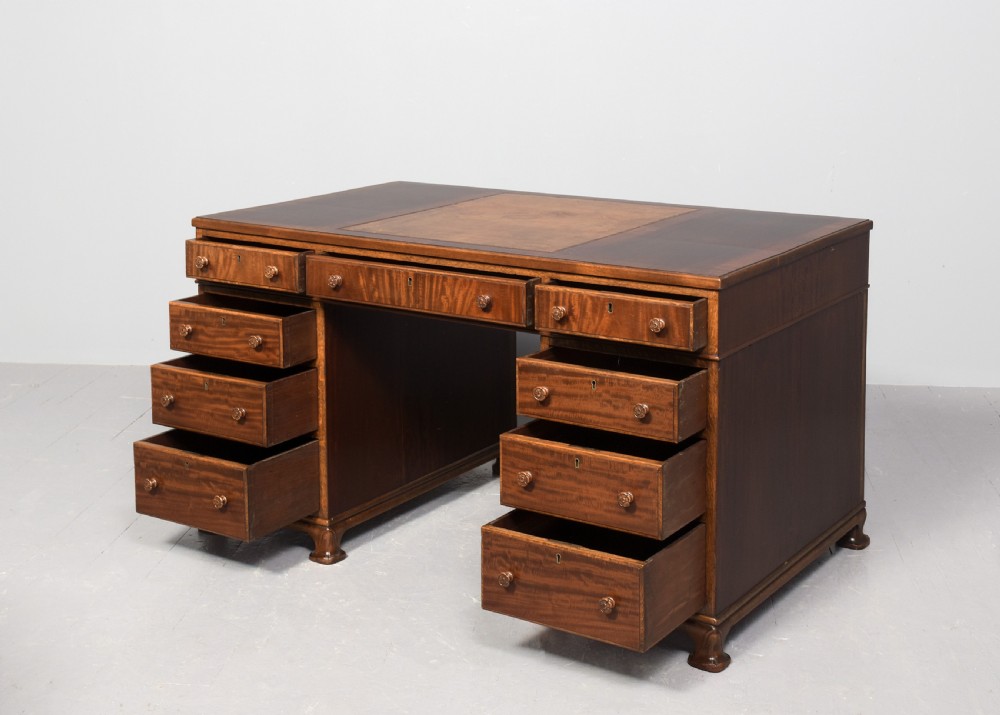 A mahogany three-part pedestal desk featuring a three-panel leather inset top, flame mahogany drawer fronts, turned wooden knobs, and bracket feet. View II