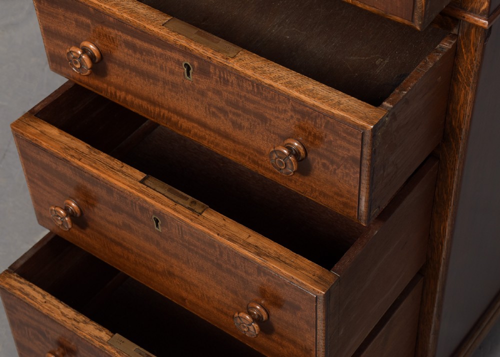 A mahogany three-part pedestal desk featuring a three-panel leather inset top, flame mahogany drawer fronts, turned wooden knobs, and bracket feet. View III