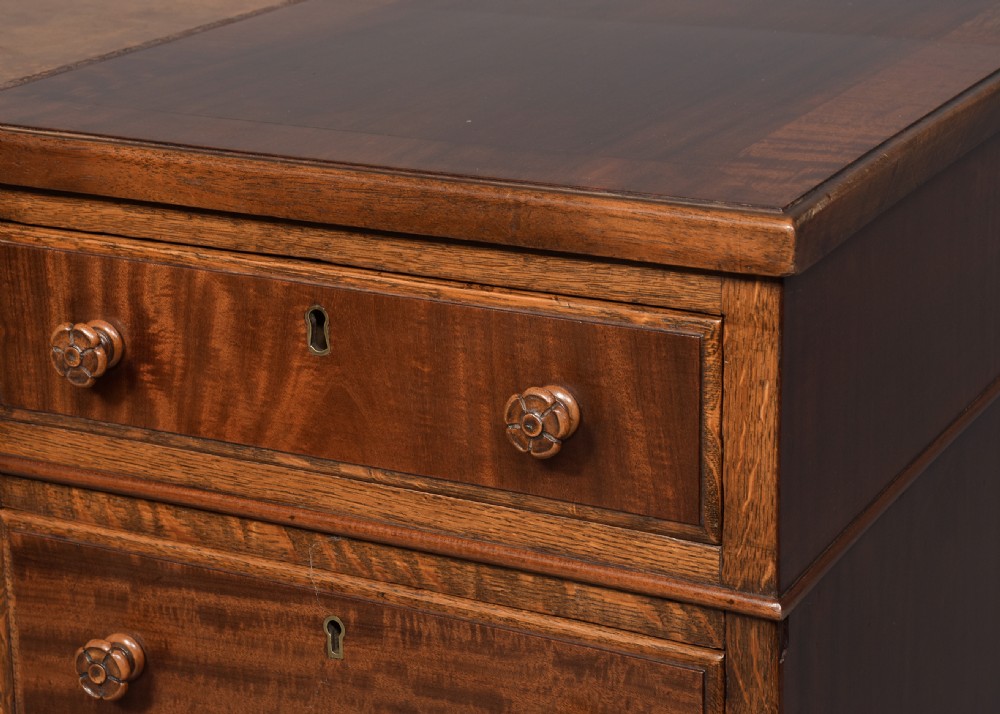 A mahogany three-part pedestal desk featuring a three-panel leather inset top, flame mahogany drawer fronts, turned wooden knobs, and bracket feet. View V